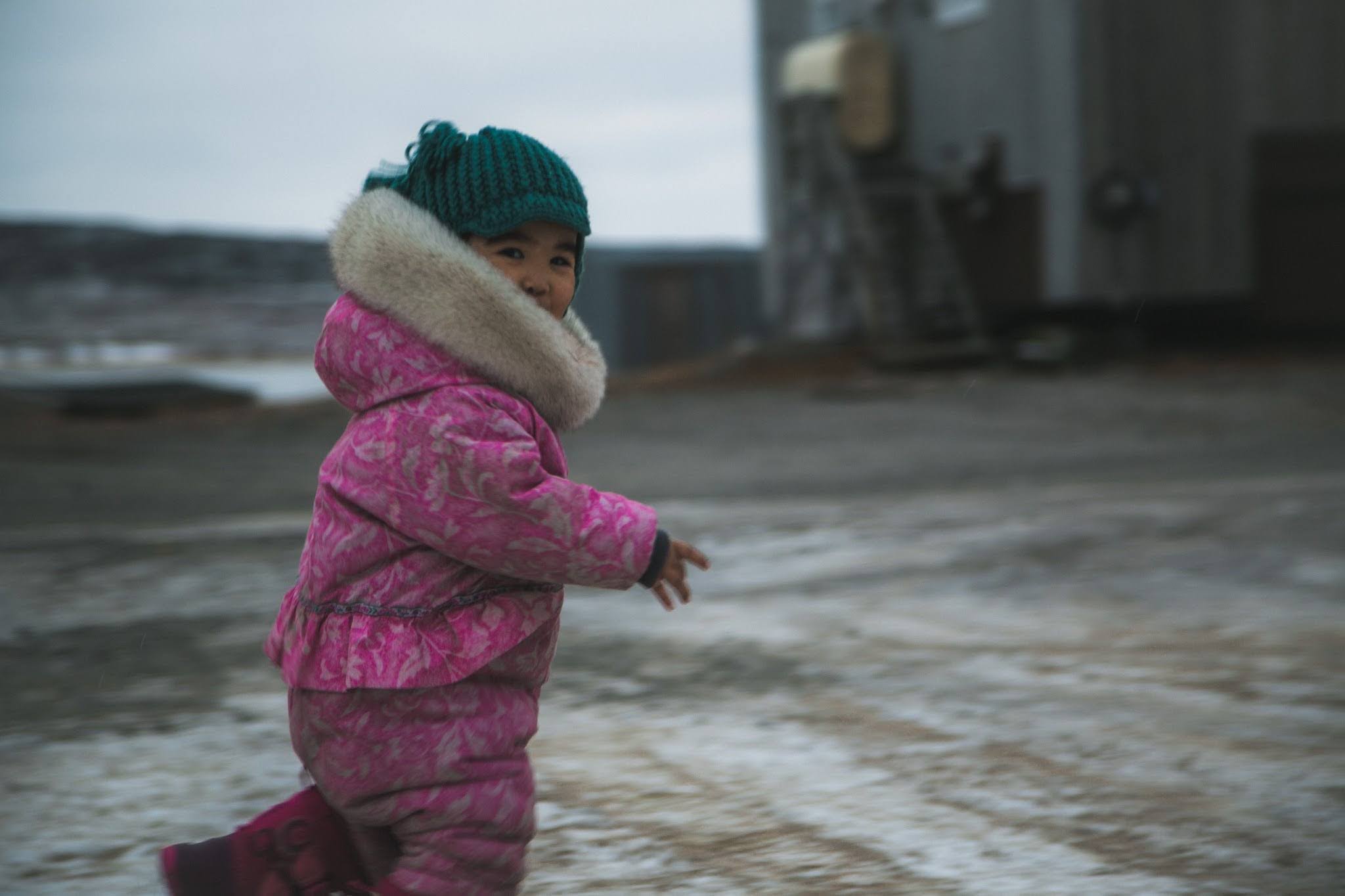 Child in pink snowsuit and turquoise toque