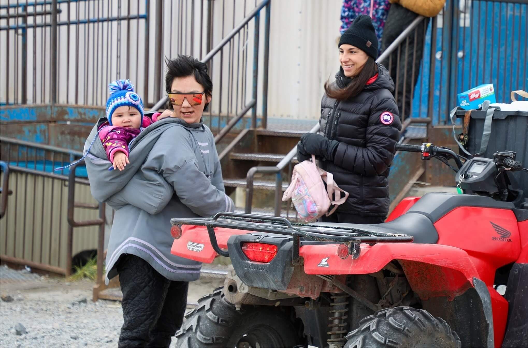 Two women and a baby next to an ATV